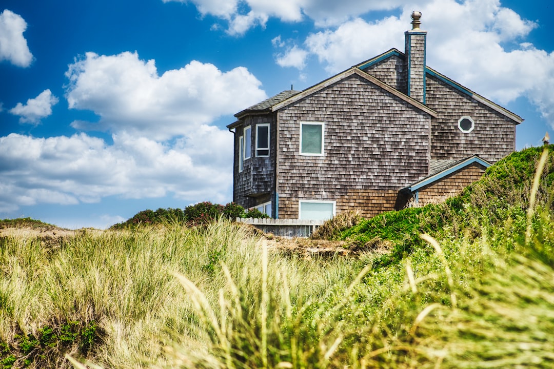 Beautiful, modern coastal home with a prominent roofline under a bright, sunny sky, representing a prime Mandeville real e...