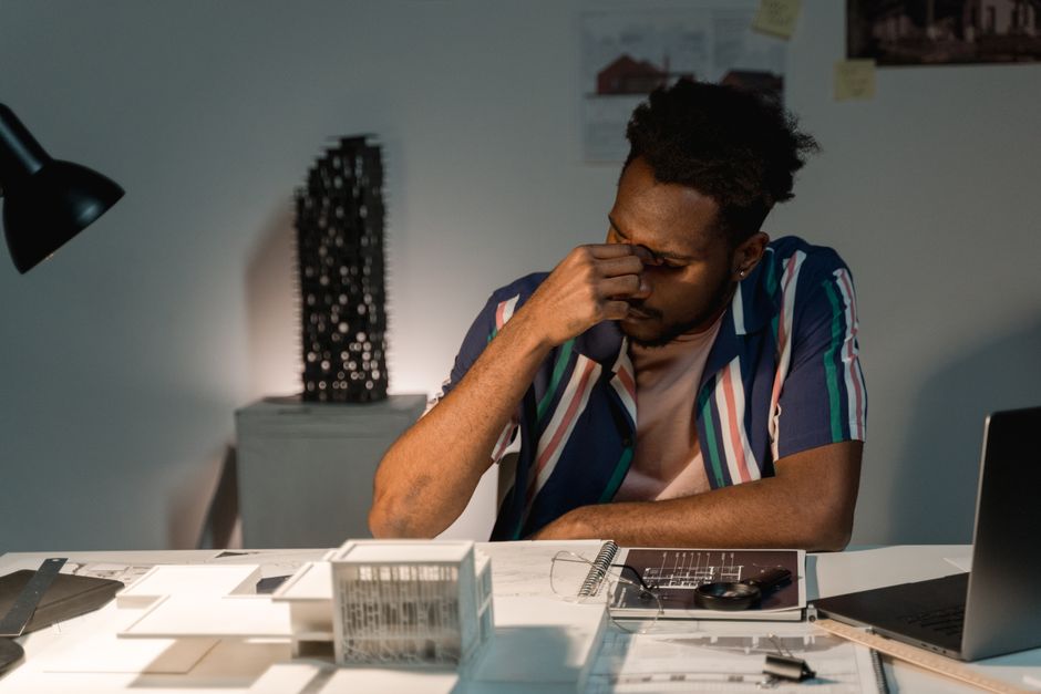 Person with a concerned expression looks over architectural blueprints, symbolizing the anxiety of making a major real est...