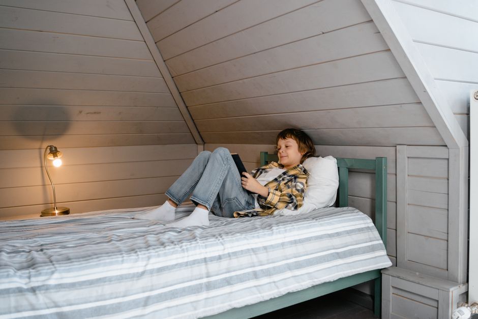 A construction worker in protective gear expertly applies spray foam insulation to the rafters of an attic, showcasing a high-ROI home upgrade.